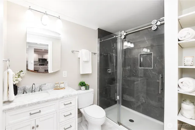 a bathroom with a shower sink vanity mirror and toilet