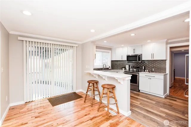a kitchen with granite countertop a refrigerator and white cabinets