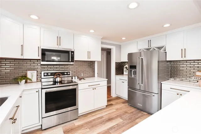 a kitchen with cabinets stainless steel appliances and wooden floor