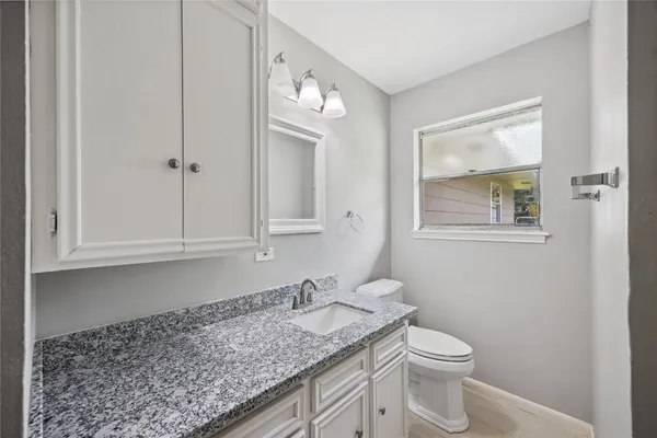 a bathroom with a granite countertop toilet sink and mirror