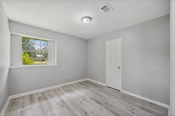 a view of an empty room with window and wooden floor