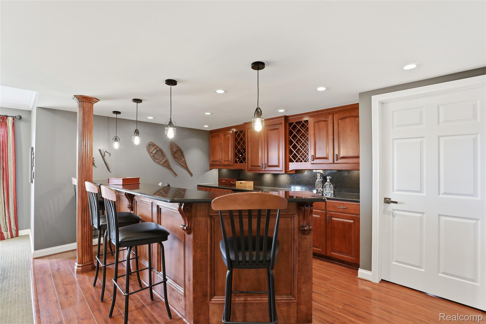 668 Springview Drive Rochester, MI 48307 - Photo 66 of 90 Kitchen featuring light wood-style flooring, decorative backsplash, hanging light fixtures, and a breakfast bar