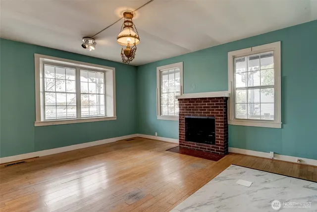 an empty room with wooden floor fireplace and windows