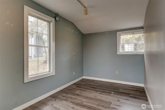 an empty room with wooden floor and windows