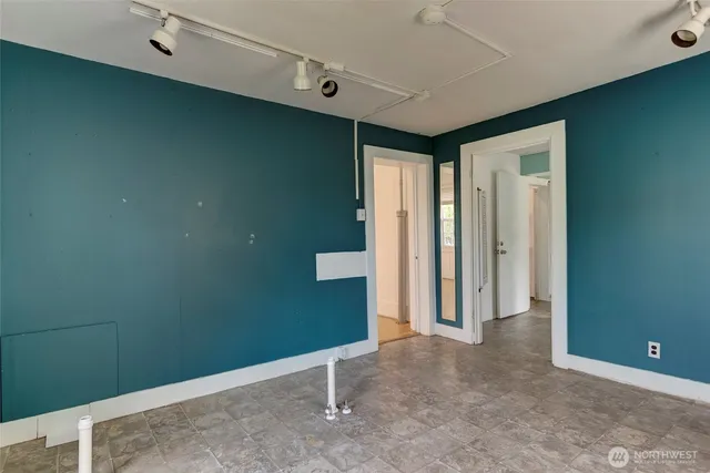 an empty room with wooden floor closet and windows