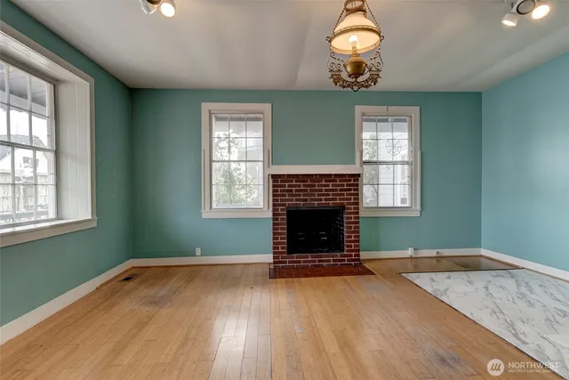 an empty room with wooden floor a fireplace and windows