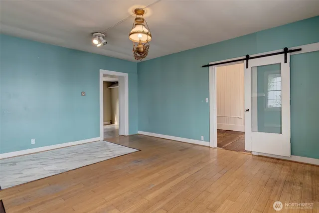 an empty room with wooden floor cabinet and windows