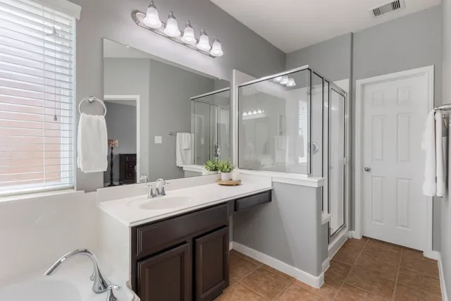 a bathroom with a bathtub a double vanity sink and mirror