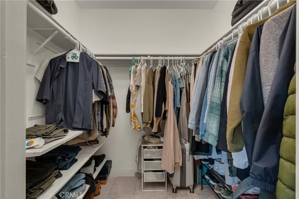 a view of walk in closet with clothes and shoes