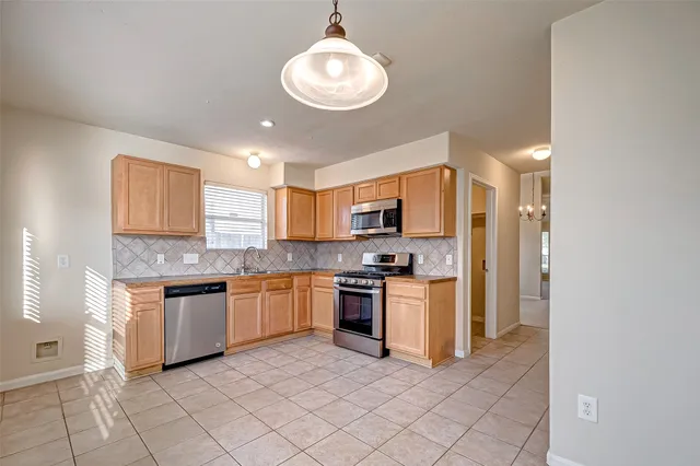 a kitchen with stainless steel appliances granite countertop a stove top oven a sink dishwasher and a refrigerator