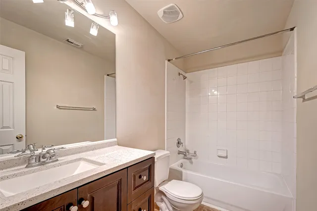 a bathroom with a granite countertop sink a toilet a mirror and shower