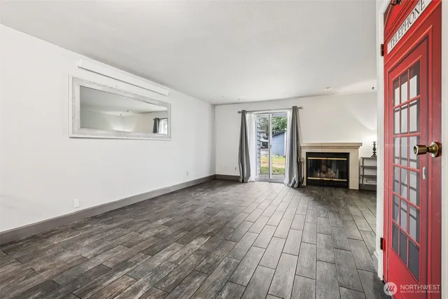 a view of an empty room with wooden floor fireplace and a window
