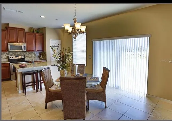 a dining room with furniture a chandelier and kitchen view