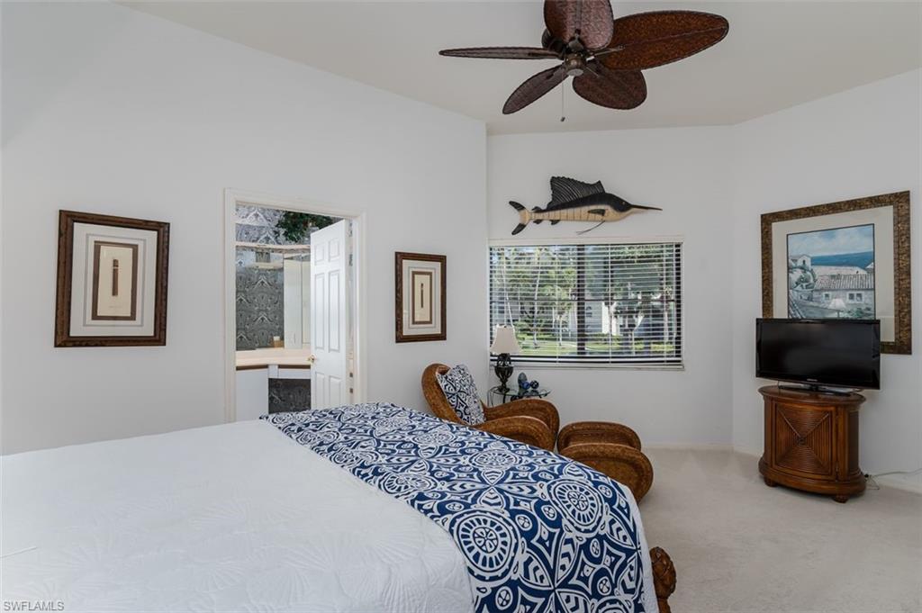 6545 Valen Way, Unit F205 Naples, FL 34108 - Photo 12 of 40 a bedroom with a bed a dresser and flat screen tv