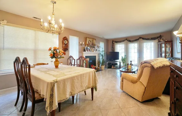 a view of a dining room with furniture a chandelier and large windows