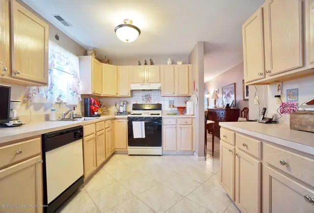 a kitchen with kitchen island granite countertop lots of white stainless steel appliances cabinets and a sink