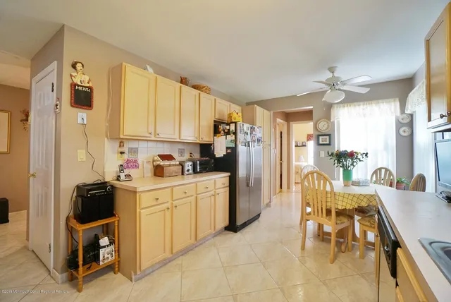 a kitchen with stainless steel appliances kitchen island granite countertop a refrigerator a stove top oven a sink a dining table and chairs with wooden floor