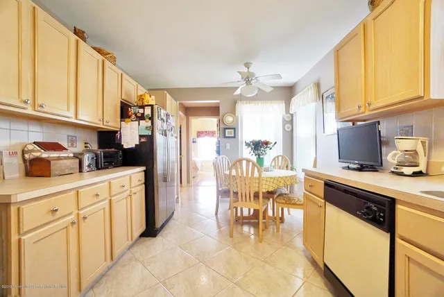 a kitchen with stainless steel appliances granite countertop a refrigerator a sink dishwasher a dining table and chairs with wooden floor