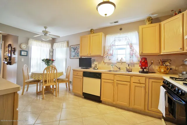 a large white kitchen with a window a sink stainless steel appliances and cabinets