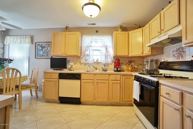 a kitchen with stainless steel appliances white cabinets a sink a stove a refrigerator and a microwave