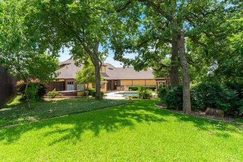 a view of a big house with a big yard and large trees