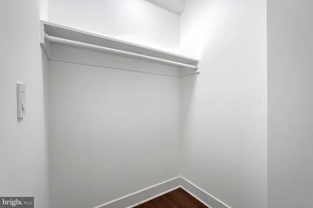 a view of a hallway with wooden floor and a kitchen