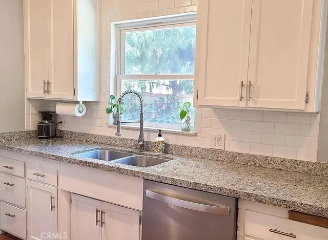 a kitchen with granite countertop white cabinets and a window