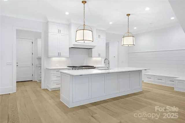 a kitchen with stainless steel appliances granite countertop a sink a stove and a wooden floors