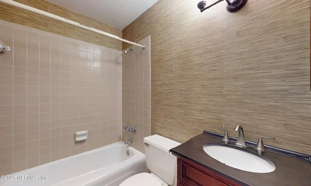 an empty room with chandelier fan and windows