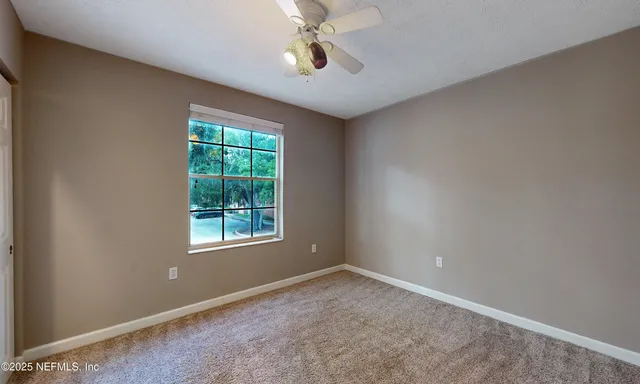 a view of an empty room with a chandelier fan