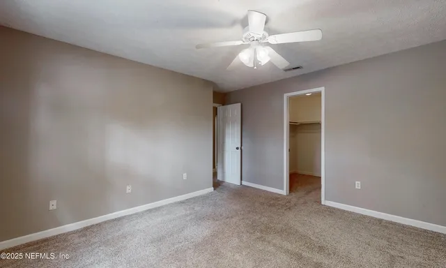 an empty room with a window and a fan