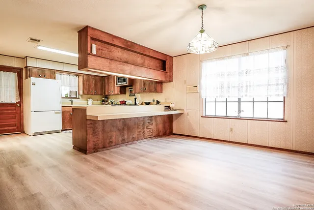 a view of a kitchen with stainless steel appliances granite countertop a stove and a large window