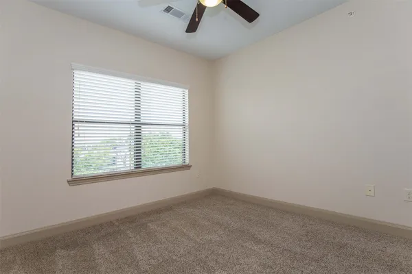 an empty room with a window and a fan