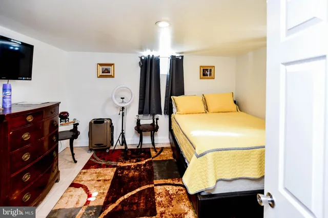 a bedroom with a bed a dresser and a potted plant