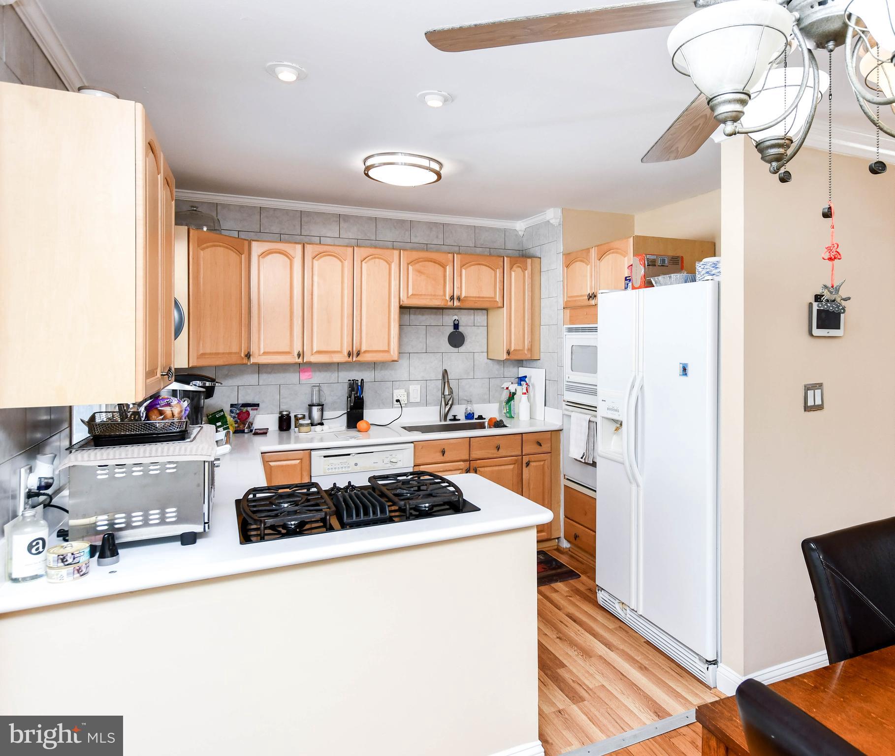 6714 Darby Road Hyattsville, MD 20784 - Photo 10 of 35 a kitchen with refrigerator a stove a sink dishwasher and white cabinets with wooden floor