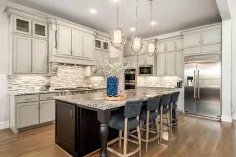 a kitchen with stainless steel appliances kitchen island granite countertop a table chairs sink and cabinets
