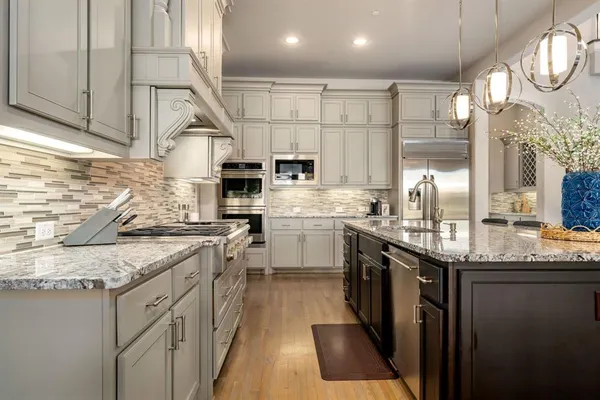 a kitchen with stainless steel appliances granite countertop a stove a sink and a microwave