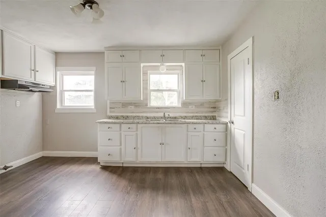 a kitchen with granite countertop white cabinets window and a sink