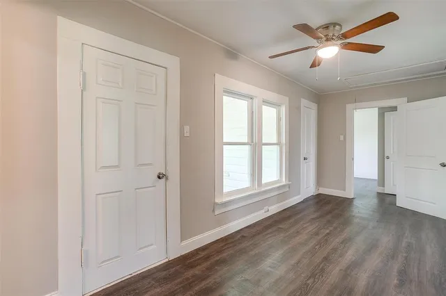 an empty room with wooden floor ceiling fan and windows