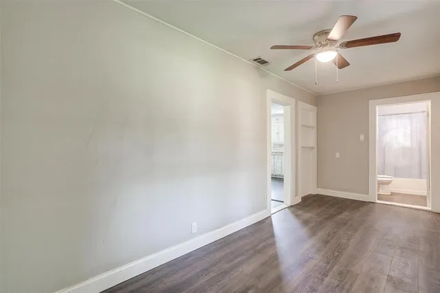 an empty room with wooden floor ceiling fan and windows