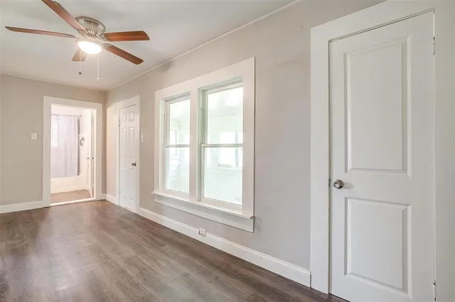 a view of an empty room with a window and wooden floor