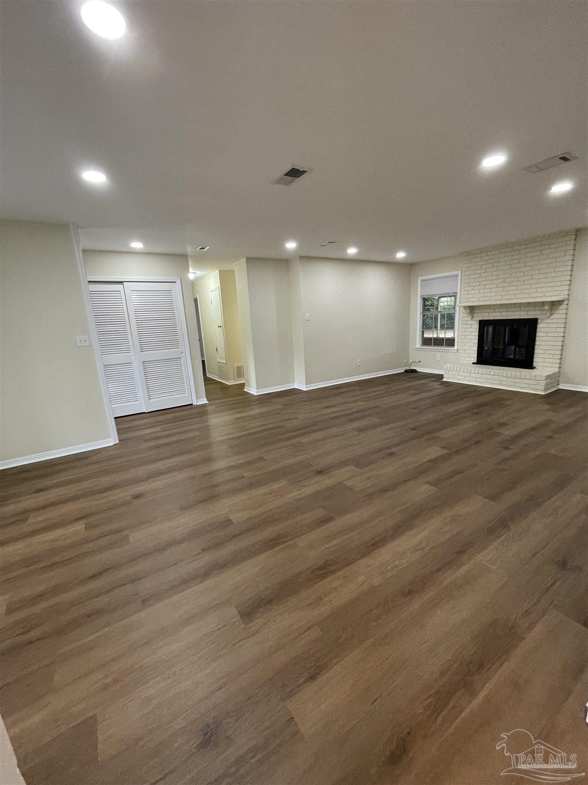4140 April Road Pensacola, FL 32504 - Photo 3 of 12 an empty room with wooden floor and fireplace