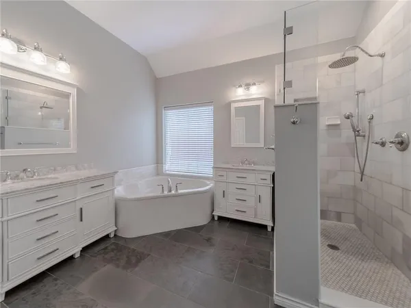 a bathroom with a tub sink shower and mirror