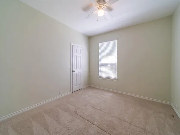 an empty room with a chandelier fan and windows