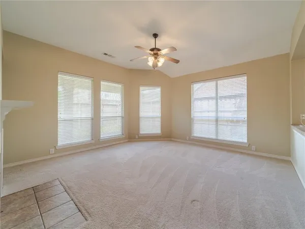 a view of an empty room with a window and a kitchen