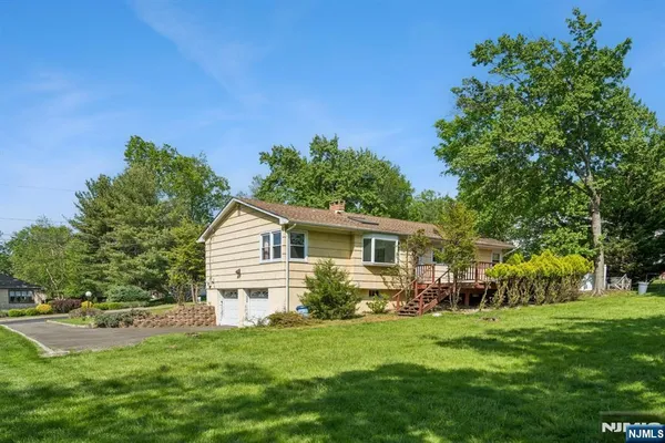 a view of a house with a big yard potted plants and large tree