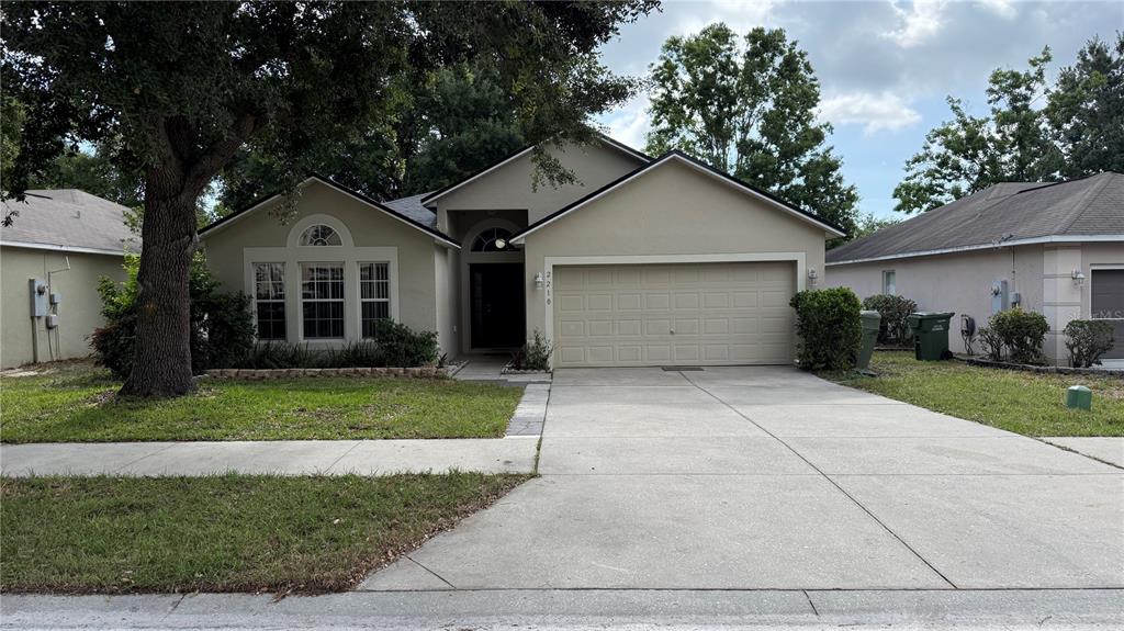 2210 Nicollett Way Leesburg, FL 34748 - Photo 1 of 31 a view of a white house with a yard plants and a large tree