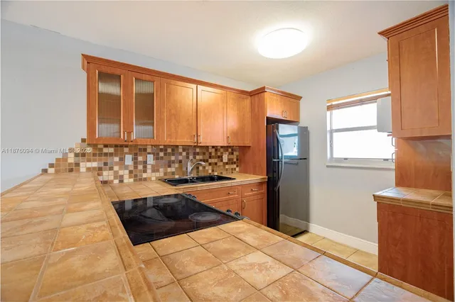 a kitchen with granite countertop a refrigerator and a stove top oven