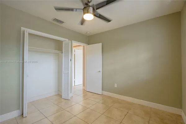 an empty room with closet and a chandelier fan