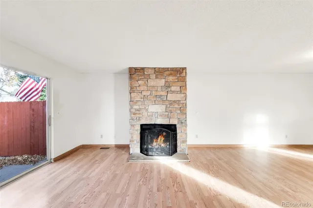 a view of empty room with wooden floor and fireplace